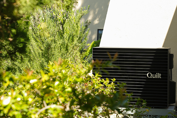 outdoor Quilt heat pump unit in front of residence